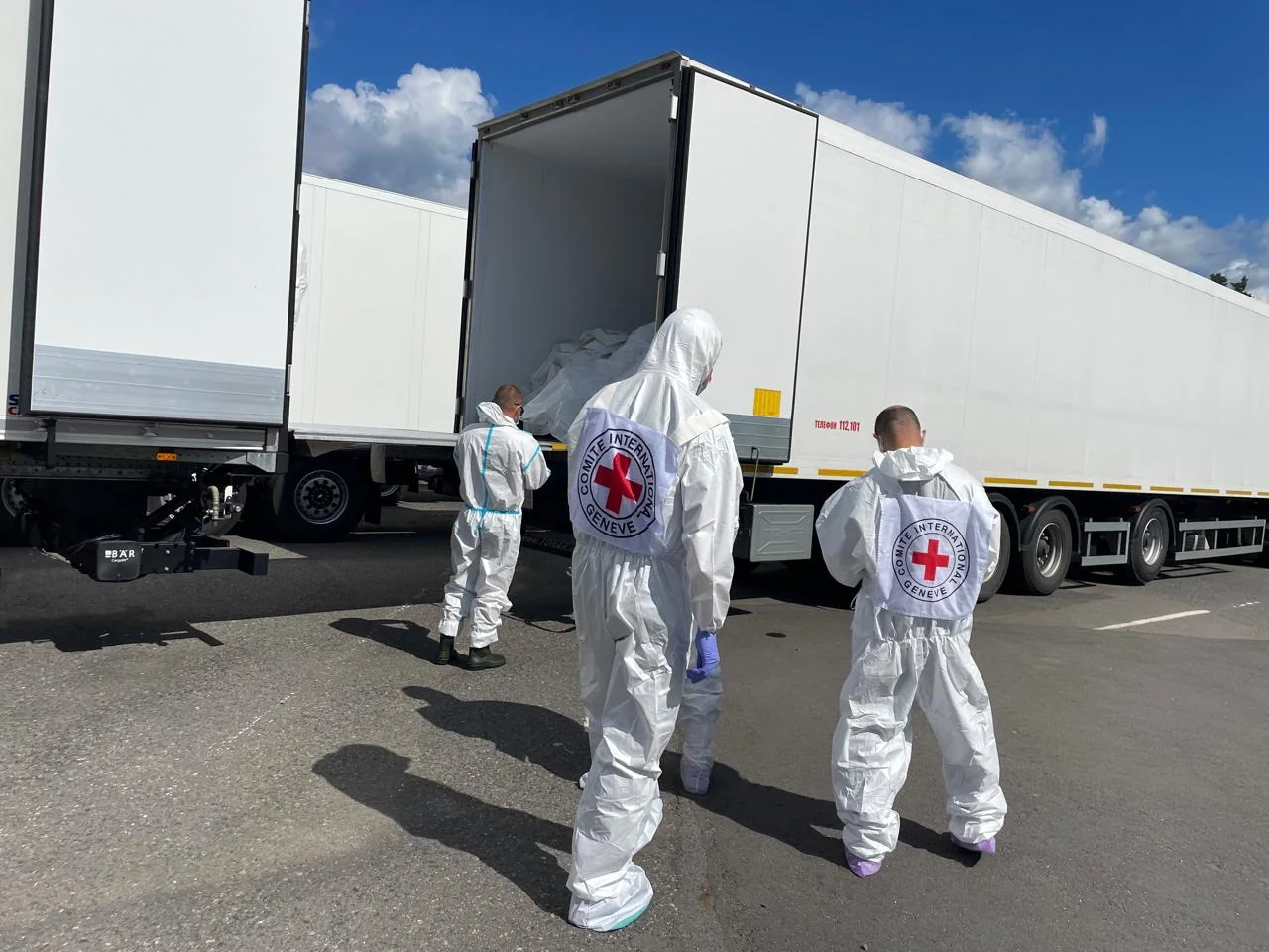 Працівники Червоного Хреста біля вантажівок з репатрійованими тілами загиблих воїнів
